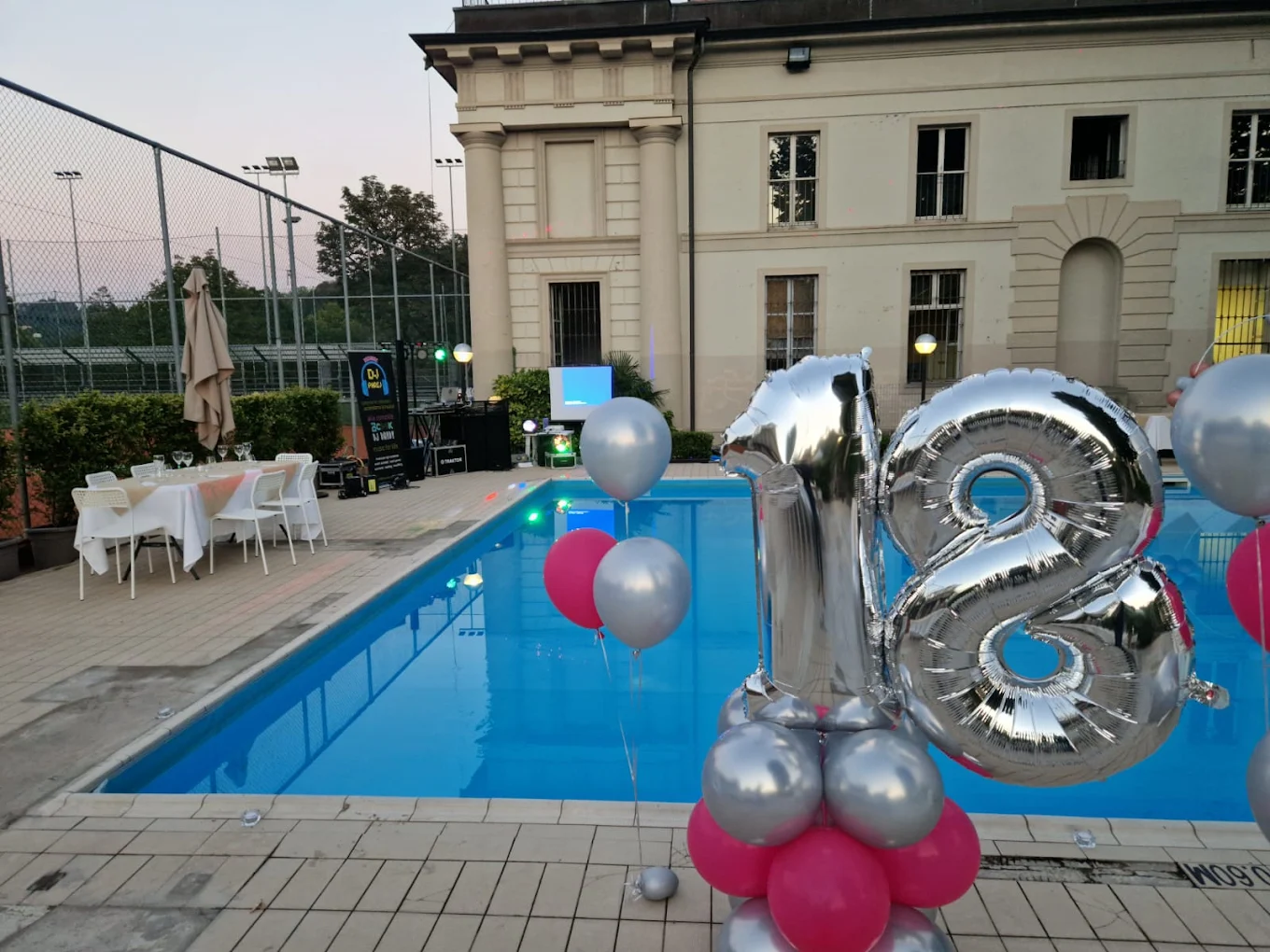 La piscina di Villa Glicini illuminata al tramonto durante una festa, Torino